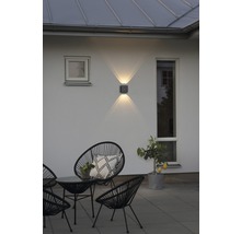 Uteplats med stolar, bord och upplyst vägglampa