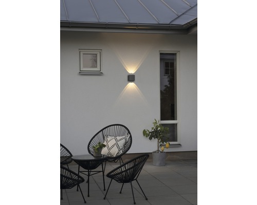 Uteplats med stolar, bord och upplyst vägglampa