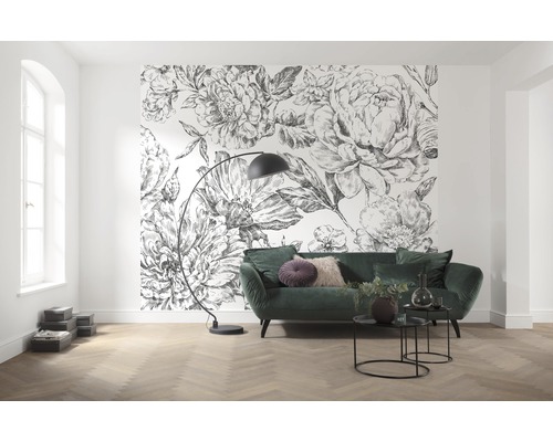 Vardagsrum med blommig tapet, grön soffa och golvlampa