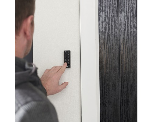 Person som använder ett elektroniskt dörrlås med knappsats på en dörr