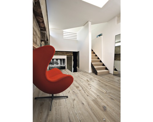 Vardagsrum med trägolv, trappa och fåtölj