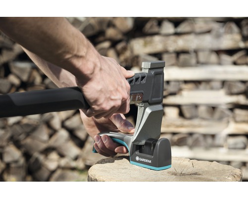 Person som vässar yxa med en yxslipare av märket Gardena.