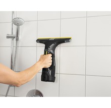 Hand använder fönsterskrapa på badrumsväggplattor