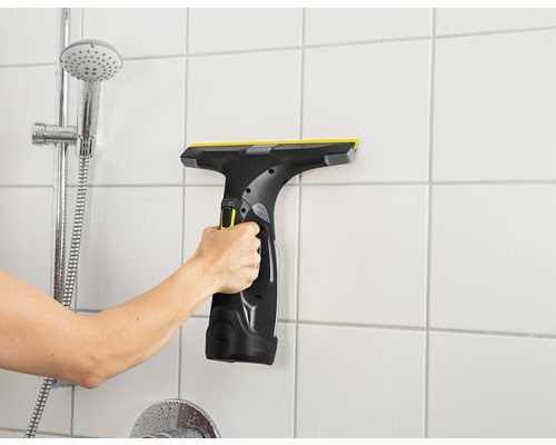 Hand använder fönsterskrapa på badrumsväggplattor