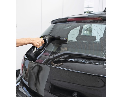 En person rengör bilens bakruta med en fönstertvätt.