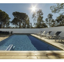 Utomhuspool med trädäck och solstolar framför träd