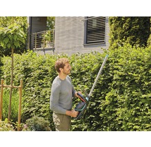 Man klipper häck med en häcksax i trädgården.