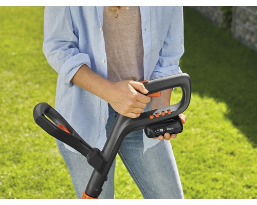 Kvinna håller i en sladdlös grästrimmer i sina händer