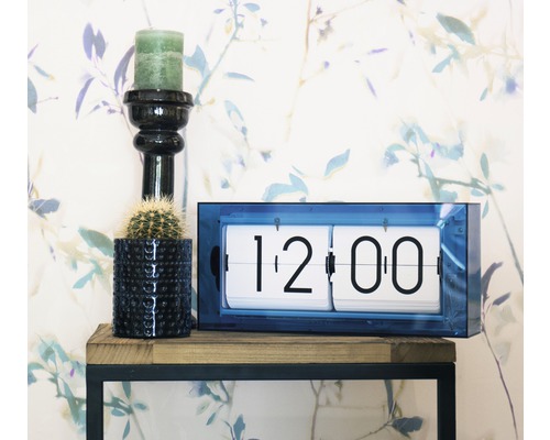 Dekorativ scen med flipklocka, ljus och kaktus på en hylla