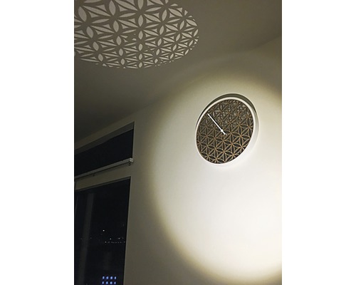 Dekorativ väggklocka med geometriskt mönster och ljuseffekt i taket