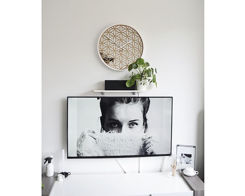 Vardagsrum med geometrisk väggklocka och TV