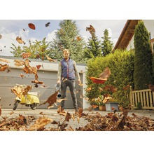 Man använder en lövblås för att ta bort löv på en gård.