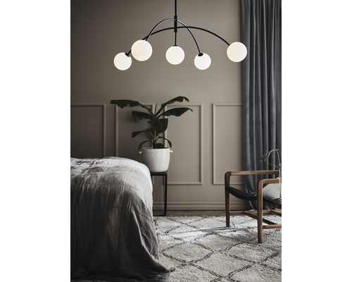 Sovrum med säng, matta, krukväxt, fåtölj och taklampa med fem lampor