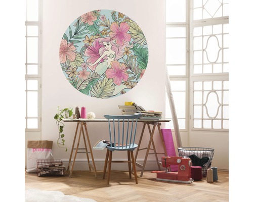 Vardagsrumsscen med en rund väggdekoration med sjöjungfru och blommönster ovanför ett bord