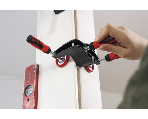 En person fixerar ett arbetsstycke med en vinkelspänningsklämma från Bessey.