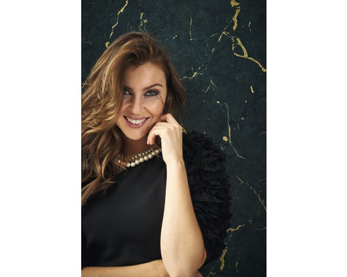 Porträtt av en leende kvinna med pärlhalsband och svart klänning