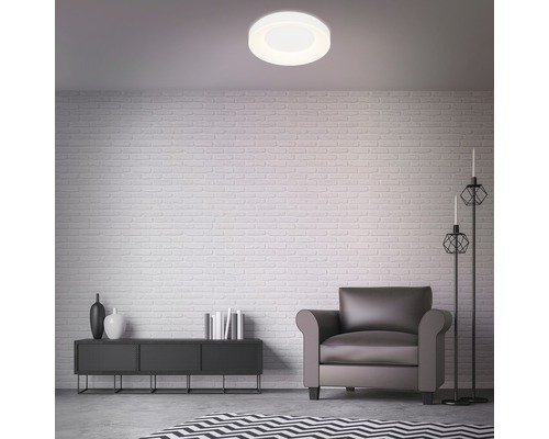 Ljust vardagsrum med taklampa, fåtölj, byrå, dekoration och matta