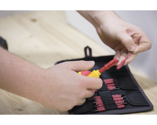 Person använder ett avisoleringsverktyg för att skala en kabel framför en verktygsväska