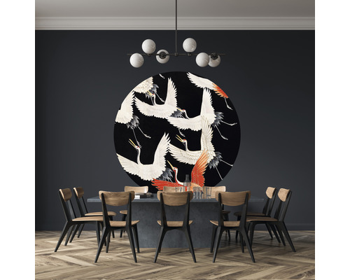 Matsal med matbord, stolar, taklampa och rund väggdekoration med tranmotiv.