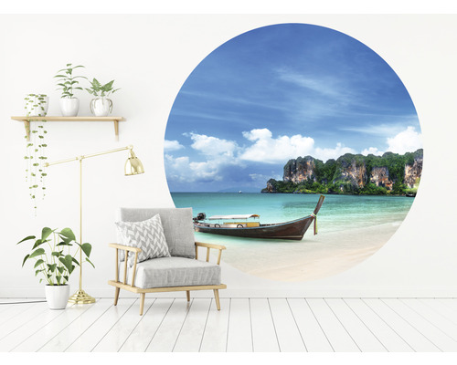 Vardagsrum med fåtölj, golvlampa, hylla med växter och väggdekal med strandmotiv