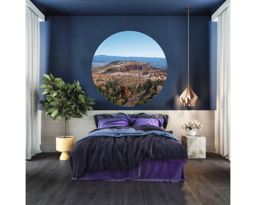 Sovrum med säng, krukväxt, lampa och runt falskt fönster med landskapsmotiv