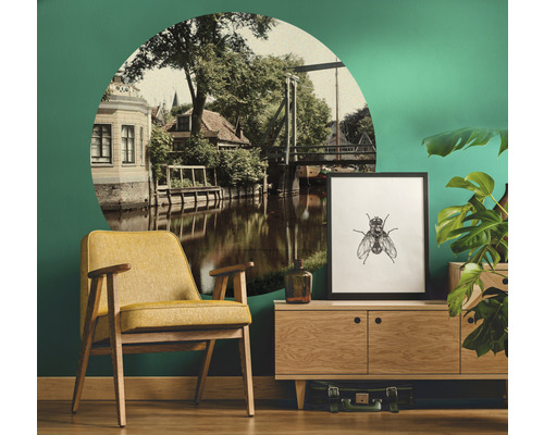 Dekorativt vardagsrum med gul fåtölj, byrå, krukväxt och väggdekal med stadsutsikt