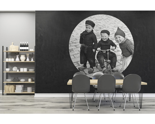 Vardagsrum med hyllor, matbord och en väggtapet med ett svartvitt barnfoto