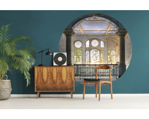 Vardagsrum med byrå, krukväxt, lampa, skiva och väggmålning av historisk byggnad