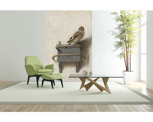 Vardagsrum med fåtölj, pall, soffbord, krukväxt och väggmålning