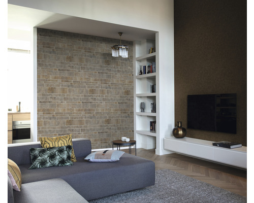 Modernt vardagsrum med stenvägg, bokhylla, grå soffa och TV