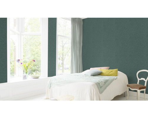 Sovrum med grön fiberdukstapet, säng, fönster och stol.