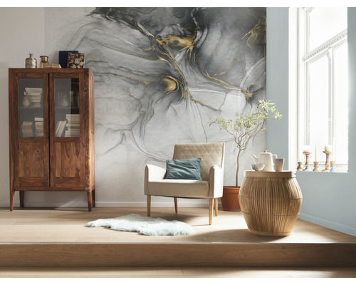 Vardagsrum med mönstrade tapeter, träskåp, fåtölj och sidobord