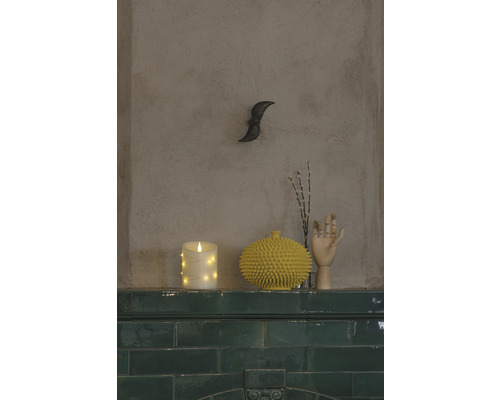 Dekorativ scen med LED-ljus, taggig vas och trähandske på en grön kakelhylla.