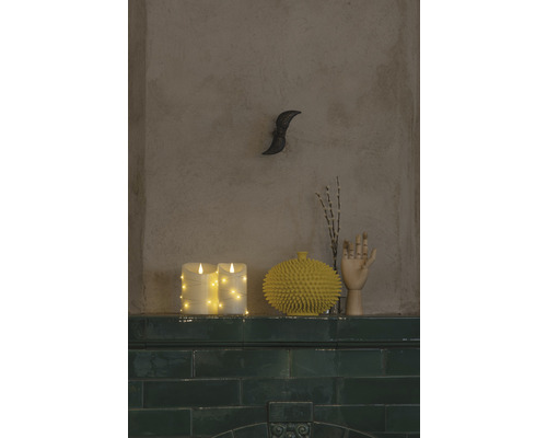 Dekorativ scen med LED-ljus, en gul vas, en trähandsmodell och en väggdekoration på en hylla.