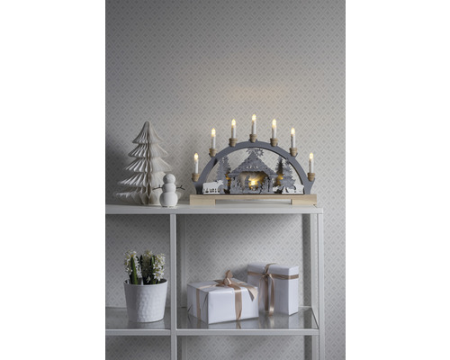 Juldekoration med ljusbåge, pappersträd, snögubbe och presenter på en hylla