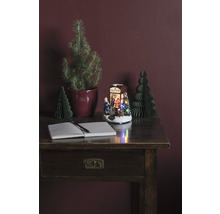 Dekorativt arrangemang med skrivbord, anteckningsbok, penna, julgranar och upplyst julscen