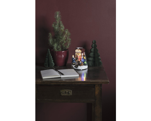 Dekorativt arrangemang med skrivbord, anteckningsbok, penna, julgranar och upplyst julscen