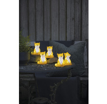 Dekorativa rävfigurer på ett trädgårdsbord med växt och kuddar