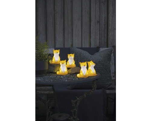 Dekorativa rävfigurer på ett trädgårdsbord med växt och kuddar