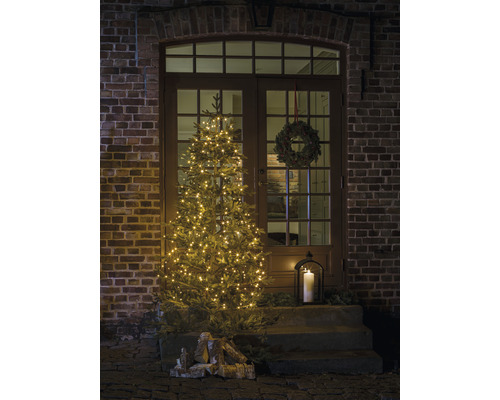 Dekorerad ytterdörr med upplyst julgran, adventskrans och lykta för festlig stämning