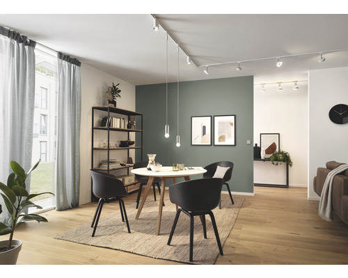 Ljust vardagsrum med matbord, stolar, hyllor och linjärt skensystem med spotlights och pendellampor