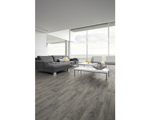 Vardagsrum med grått laminatgolv, grå soffa och stora fönster med havsutsikt