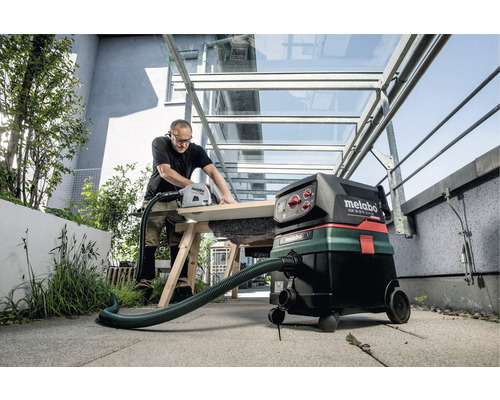 Hantverkare sågar trä med handsåg och industridammsugare