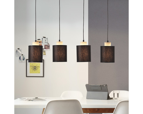 Hänglampa med fyra lampor och cylindriska lampskärmar ovanför ett matbord