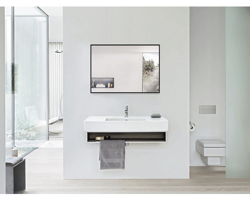 Modernt badrum med handfat, spegel och toalett i ljusa färger