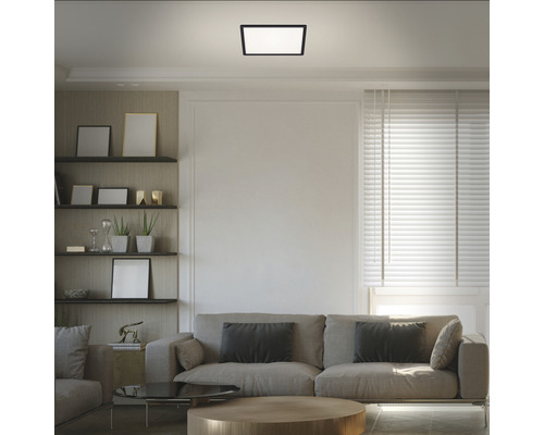 Vardagsrum med soffa, hyllor och fyrkantig taklampa