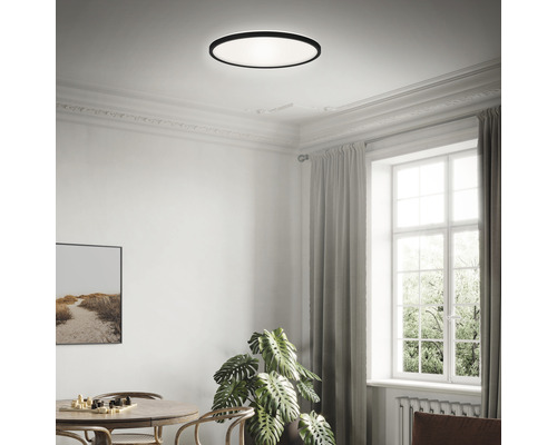 Ett ljust rum med en rund taklampa, ett bord och ett fönster.