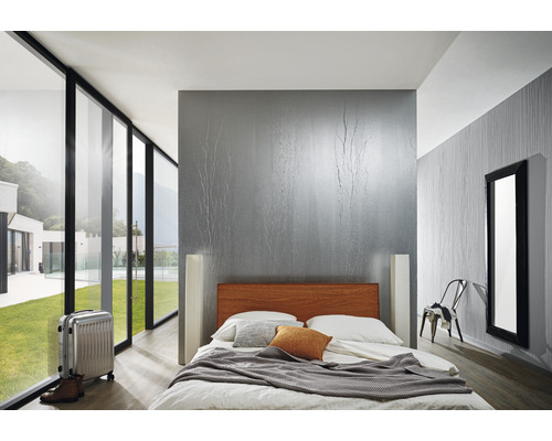 Ljust sovrum med säng, resväska och stort fönster med utsikt över grönska