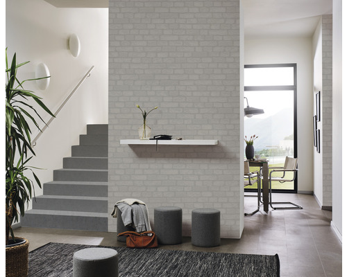 Ljus hall med tegelmönstrad tapet, trappa, bord och stolar.