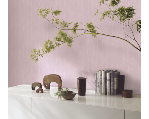 Vardagsrumsmiljö med mönstrad tapet, böcker och dekoration på en skänk